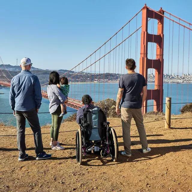 마린 헤드랜즈(Marin Headlands)에서 금문교(Golden Gate Bridge)를 바라볼 때 휠체어를 탄 한 사람을 포함한 한 무리의 사람들이 뒤에서 보입니다.